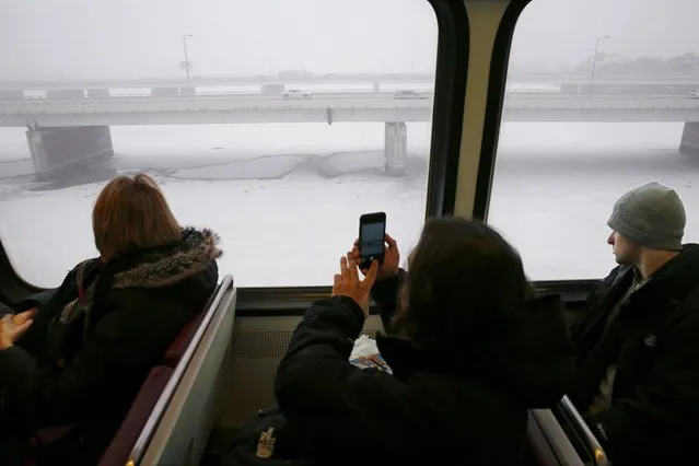 A Metro subway rider takes a picture of the snow-covered Potomac River as a snow falls in Washington January 22, 2016. A powerful storm arrived Washington on Friday, threatening to bury parts of the East Coast under as much as 30 inches of snow after coating North Carolina in white and blasting Arkansas, Tennessee and Kentucky with a wintry mix. (Photo by Jonathan Ernst/Reuters)