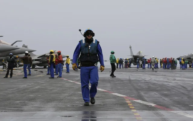 In this Wednesday, March 18, 2015 photo, French sailors work on the flight deck of the French Navy aircraft carrier Charles de Gaulle in the Persian Gulf. (Photo by Hasan Jamali/AP Photo)