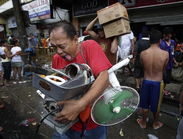 A man reacts after getting supplies from a grocery that was stormed by people in Tacloban city. (Photo by Aaron Favila/Associated Press)