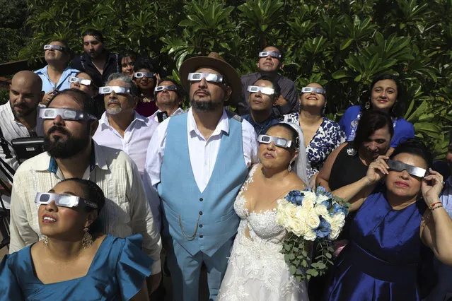 Isaac Medina, center, and Jazmin Gonzalez, center right, watch a “ring of fire” solar eclipse before their wedding ceremony in Merida, Mexico, Saturday, October 14, 2023. The annular eclipse dimmed the skies over parts of the western U.S. and Central and South America. (Photo by Martin Zetina/AP Photo)