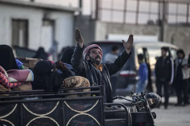 A Syrian man gestures as Syrians gather at the border gate with Turkey, in Bab al-Salam, Syria, Saturday, February 6, 2016. Thousands of Syrians have rushed toward the Turkish border, fleeing fierce Syrian government offensives and intense Russian airstrikes. Turkey has promised humanitarian help for the displaced civilians, including food and shelter, but it did not say whether it would let them cross into the country. (Photo by Bunyamin Aygun/AP Photo)