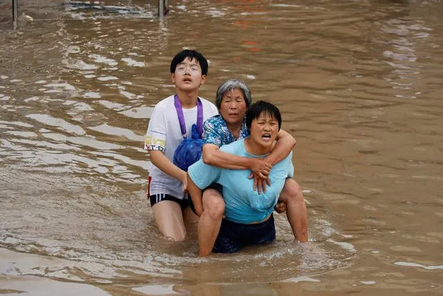 A woman carries an elderly woman as they make their way through floodwaters following heavy rainfall in Zhengzhou, Henan province, China July 23, 2021. (Photo by Aly Song/Reuters)
