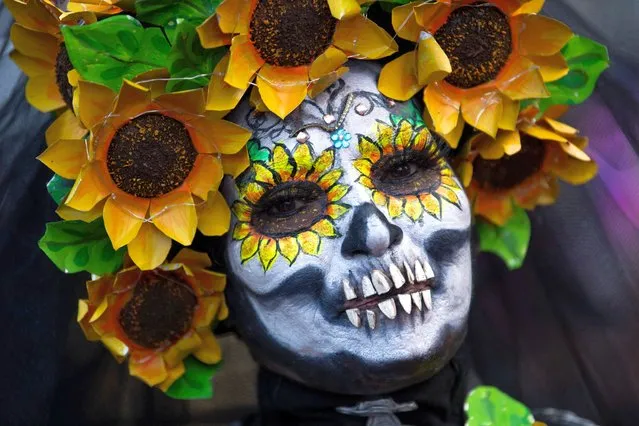 A woman fancy dressed as the character of La Catrina poses before taking part in the Catrinas Parade, commemorating the Day of the Dead, in Mexico City, on October 23, 2022. (Photo by Claudio Cruz/AFP Photo)
