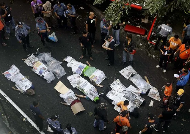 Bodies of passengers are covered with newspapers as they are laid down on the road after the passenger bus they were in plunged from an elevated highway in suburban Paranaque, Philippines, on December 16, 2013. (Photo by Bullit Marquez/Associated Press)