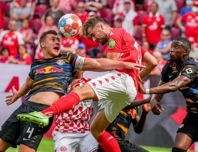 Mainz's Alexander Hack, center, and Leipzig's Willi Orban, left, fight for the ball during the German Bundesliga soccer match between FSV Mainz 05 and RB Leipzig in Mainz, Germany, Sunday, August 15, 2021. (Photo by Michael Probst/AP Photo)
