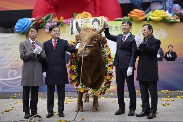 South Korean financial officers pose with a bull to celebrate the opening for the Year 2024 trading outside of the Korea Exchange in Seoul, South Korea, Tuesday, January 2, 2024. (Photo by Lee Jin-man/AP Photo)