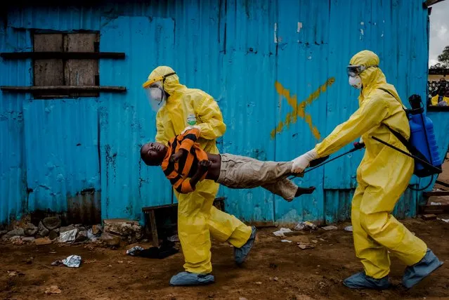Medical staff carry James Dorbor, 8, suspected of having Ebola, into a treatment facility in Monrovia, Liberia, September 5, 2014. (Photo by Daniel Berehulak/Reuters/The New York Times)