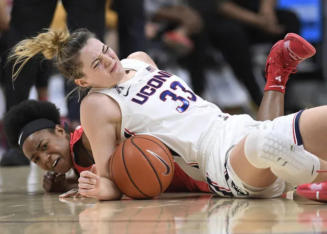 Connecticut's Katie Lou Samuelson, top and Houston's Julia Blackshell-Fair fall to the court chasing a loose ball during the first half of an NCAA college basketball game, Saturday, March 2, 2019, in Storrs, Conn. Samuelson left the game injured after the play. (Photo by Jessica Hill/AP Photo)