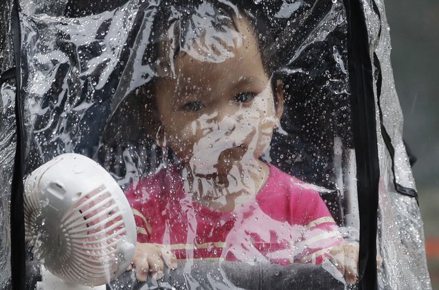 A baby looks out through the raindrop canopy in a rain caused by Typhoon Chanthu in Taipei, Taiwan, Sunday, September 12, 2021. Typhoon Chanthu drenched Taiwan with heavy rain Sunday as the storm’s center passed the island’s east coast heading for Shanghai. (Photo by Chiang Ying-ying/AP Photo)