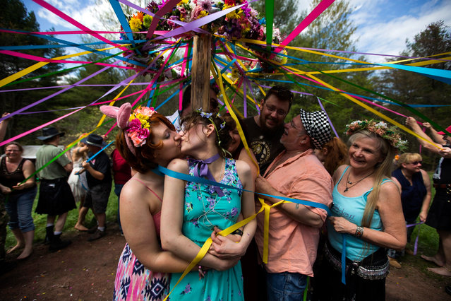 Chance Forney (L) kisses Sam Hunsicker (C-L) as church members wrap them and others in ribbons from a maypole  during a Beltaine celebration at Four Quarters Interfaith Sanctuary in Artemas, Pennsylvania, USA, 02 May 2015. The sanctuary, which has hundreds of members, bills itself as a “safe and sacred ceremonial space for the modern practice of ancient religion”. (Photo by Jim Lo Scalzo/EPA)