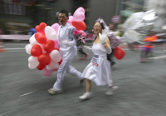 A couple wearing wedding costumes races with heart-shaped balloons in the Tokyo Marathon Tokyo Sunday, February 23, 2014. (Photo by Eugene Hoshiko/AP Photo)