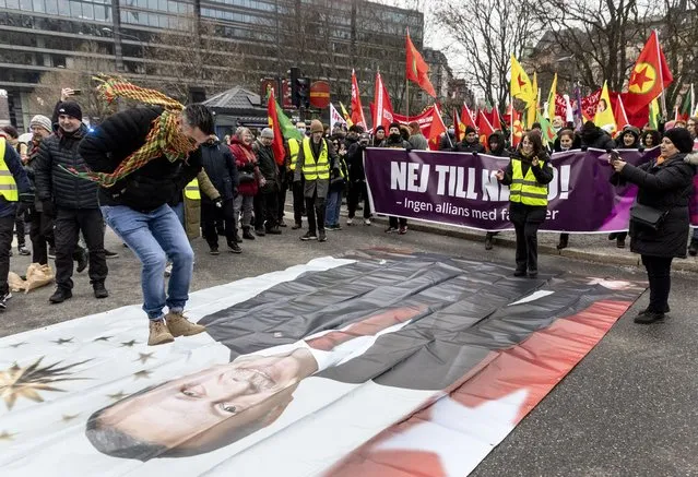 A protestor prepares to jump on a banner with the image of Turkish President Recep Tayyip Erdogan during a demonstration organised by The Kurdish Democratic Society Center in Sweden, as Sweden seeks Turkey's approval to join NATO, in Stockholm, Saturday, January 21, 2023. Demonstrations took place in Sweden that could complicate its efforts to persuade Turkey to approve its NATO accession. A far-right activist from Denmark has received permission from police to stage a protest on Saturday outside the Turkish Embassy, where he intends to burn the Quran, Islam’s holy book. (Photo by Christine Olsson/TT News Agency via AP Photo)
