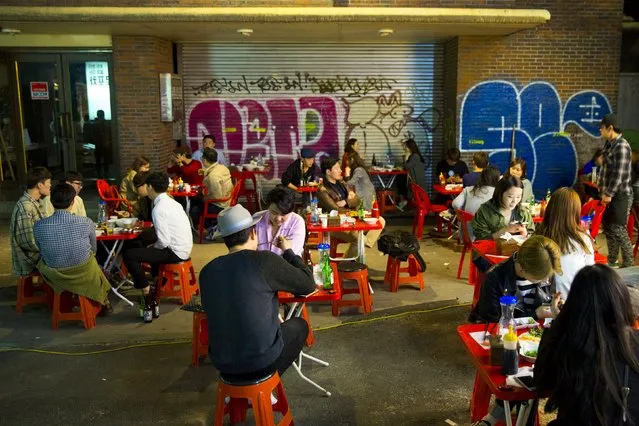 People sit in a streat restaurant in the trendy nightlife district of Hongdae in Seoul, May 9, 2015. (Photo by Thomas Peter/Reuters)