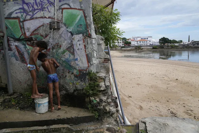 Children rinse the sand off their bodies after spending the day at the beach, during the celebration of the country's Bicentennial of its independence from Spain, at Casco Viejo neighborhood in Panama City, Sunday, November 28, 2021. (Photo by Arnulfo Franco/AP Photo)