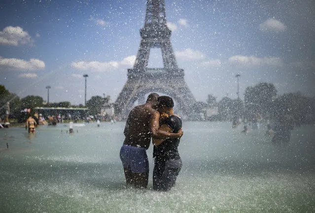 A couple cool down in the fountains of Trocadero, across from the Eiffel Tower, during a heatwave in Paris, France, 25 June 2019. According to forecasters, the temperatures should rise to almost 40 degrees Celsius in the coming days. (Photo by Ian Langsdon/EPA/EFE)