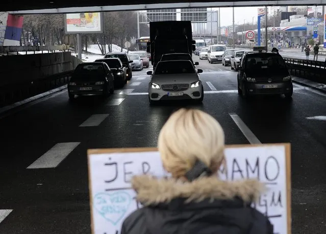 A demonstrator blocks a highway, during a protest in Belgrade, Serbia, Saturday, January 15, 2022. Hundreds of environmental protesters demanding cancelation of any plans for lithium mining in Serbia took to the streets again, blocking roads and, for the first time, a border crossing. Traffic on the main highway north-south highway was halted on Saturday for more than one hour, along with several other roads throughout the country, including one on the border with Bosnia. (Photo by Darko Vojinovic/AP Photo)