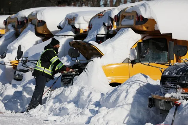 An employee tries to start the engine of a school bus after Toronto District School Board (TDSB) facilities were shut for a second day due to heavy snowfall, at Stock Transportation in Scarborough, Ontario, Canada, January 18, 2022. (Photo by Chris Helgren/Reuters)