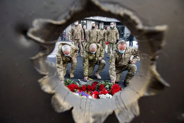 People attend a ceremony in tribute to fallen defenders of Ukraine, including the soldiers killed during a battle with pro-Russian rebels for the Donetsk airport this day in 2015, at a memorial near the headquarters of the Defence Ministry in Kyiv, Ukraine on January 20, 2022. (Photo by Ukrainian Presidential Press Service/Handout via Reuters)