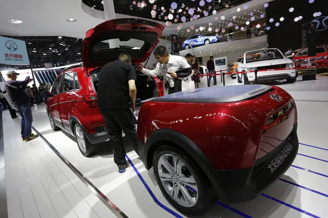Visitors examine the Chinese automaker BAIC EX200 powered by solar power on display at the Beijing International Automotive Exhibition in Beijing, Monday, April 25, 2016. (Photo by Andy Wong/AP Photo)