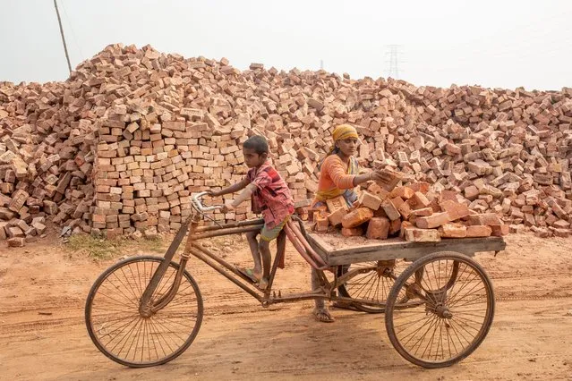 A Bangladeshi female laborer and her child work at the brick field in Aminbazar, Dhaka area, Bangladesh, 21 January 2022. Dhaka continues to be ranked as one of the world's most polluted cities, with debris from construction, vehicle emmisions and brick kilns listed as major contributors to air pollution in the city. (Photo by Monirul Alam/EPA/EFE)