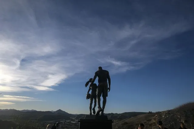 A bronze sculpture honoring former Los Angeles Lakers NBA basketball player Kobe Bryant, his daughter Gianna Bryant, and the names of those who died, is displayed at the site of a 2020 helicopter crash sits in a hillside in Calabasas, Calif, on Wednesday, January 26, 2022. (Photo by Ringo H.W. Chiu/AP Photo)