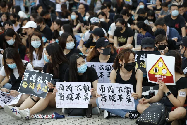 Workers from the medical and health care sector hold up signs that reads: “Citizens won't leave, medics won't abandon” during a demonstration in Hong Kong Friday, Aug. 2, 2019. Protesters plan to return to the streets again this weekend, angered by the government's refusal to answer their demands, violent tactics used by police – possibly in coordination with organized crime figures. (Photo by Vincent Thian/AP Photo)