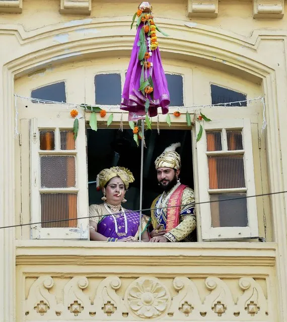 A man and woman dressed up in traditional attire watch as people throng the streets in Mumbai to celebrate the Maharashtrian new year “Gudi Padwa” in Thane, India on Tuesday, March 28, 2017. (Photo by Press Trust of India)