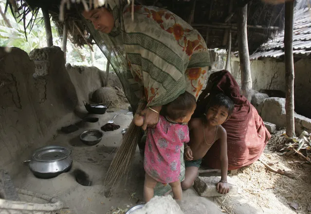 A woman, with her children, works inside her kitchen in Nandigram village, about 125 km southwest from Kolkata, February 1, 2007. (Photo by Parth Sanyal/Reuters)