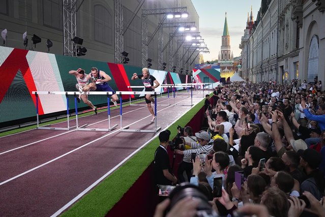 Athletes compete in the men's 60-meter hurdles during the first day of the Week of track and field in Nikolskaya street near the Kremlin, background, and Red Square in Moscow, Tuesday, June 4, 2024. (Photo by Alexander Zemlianichenko/AP Photo)