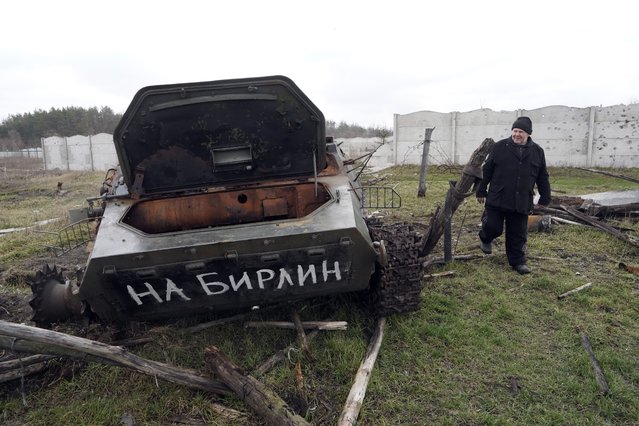 A local man walks past a destroyed Russian armoured vehicle with writing reading “towards Berlin” in liberated village Ruski Tyshky, Ukraine, Monday, March 27, 2023. After the winter, many residents of the liberated territories of the Kharkiv region return home to rebuild their homes after the fighting between the Russian and Ukrainian armed forces. (Photo by Andrii Marienko/AP Photo)