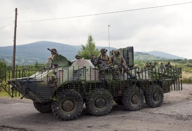 Ukrainian government servicemen ride on top of an armoured personnel carrier (APC) during search for members of Right Sector in the village of Bobovyshche near Mukacheve, Ukraine, July 13, 2015. (Photo by Reuters/Stringer)