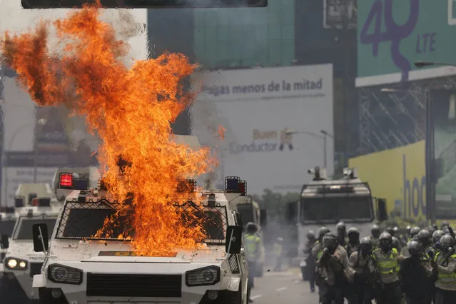 An armored police vehicle catches fires from molotov bombs thrown by anti-government protesters in Caracas, Venezuela, Wednesday, April 26, 2017. (Photo by Fernando Llano/AP Photo)