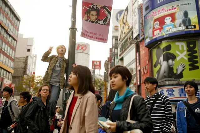 A boy stands on a post to take pictures of Shibuya junction, which is popular among tourists, in Tokyo, Japan, March 30, 2016. (Photo by Thomas Peter/Reuters)