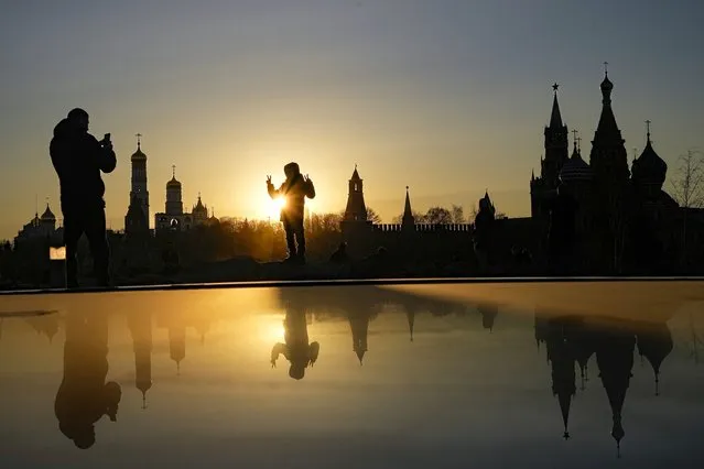 A woman poses for a photo during sunset over the Kremlin at Zaryadye Park near Red Square in Moscow, Russia, Wednesday, March 23, 2022. (Photo by AP Photo/Stringer)