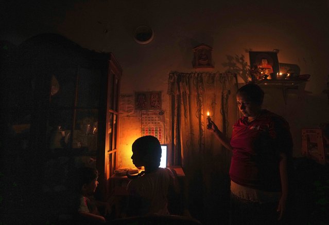 A Sri Lankan mother interacts with her children as they attend online lessons with a help of kerosine oil lamp during a power cut in Colombo, Sri Lanka, Friday, March 4, 2022.. Sri Lanka is going through hours of daily power cuts since it can’t operate turbines because of a fuel shortage and the government has only a little foreign currency to pay for oil imports. The country has no power for 7 1/2 hours a day, forcing children to study under homemade kerosene oil lamps, fishermen to limit fishing and shops and industries to limit production and business. (Photo by Eranga Jayawardena/AP Photo)