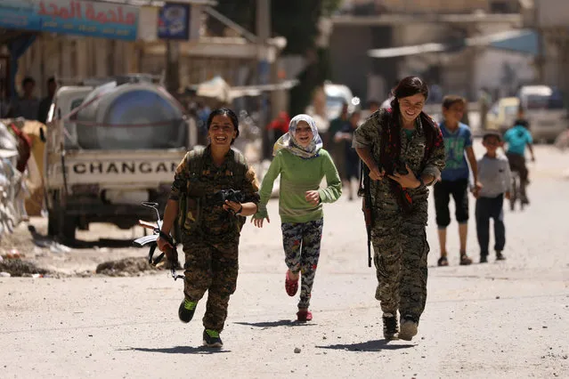 Syrian Democratic Forces (SDF) women fighters run with chidlren in the town of Tabqa, after SDF captured it from Islamic State militants this week, Syria May 12, 2017. (Photo by Rodi Said/Reuters)