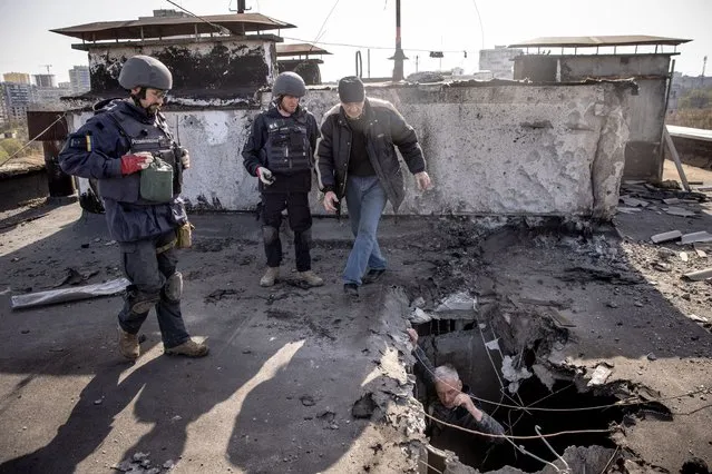 A resident shows deminers the site of an empty rocket that struck the roof of a residential building as they clear the area on April 15, 2022 in Kharkiv, Ukraine. After Russian forces retreated from areas around Kyiv, recent reports point to a new offensive as Russian forces have regrouped in the eastern part of the country bringing fears of an escalation of violence.  (Photo by Chris McGrath/Getty Images)
