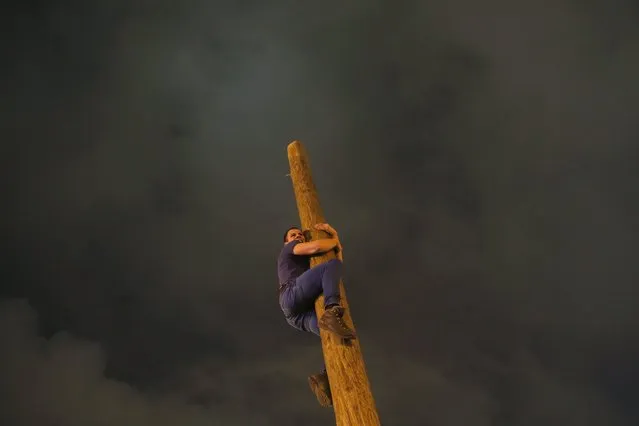A man climbs up a wooden pole during Maslenitsa celebrations at Gorky park in Moscow, Russia, March 13, 2016. Maslenitsa is widely viewed as a pagan holiday marking the end of winter and is celebrated with pancake eating and shows of strength, while the Orthodox Church considers it as the week of feasting before Lent. (Photo by Maxim Shemetov/Reuters)