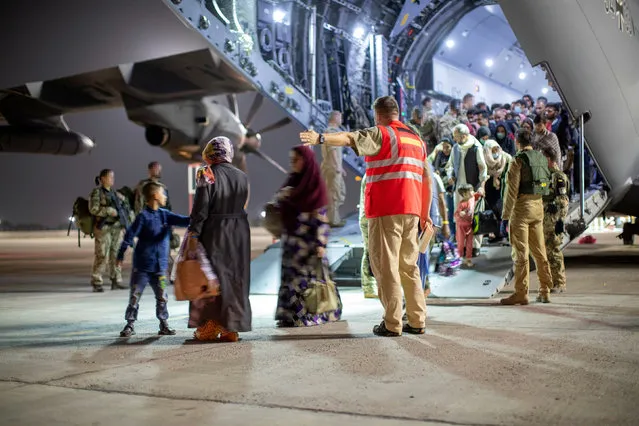 Staff talk to evacuees from Afghanistan as they arrive in an Airbus A400 transport aircraft of the German air force in Tashkent, Uzbekistan on August 21, 2021. (Photo by Marc Tessensohn/Reuters)