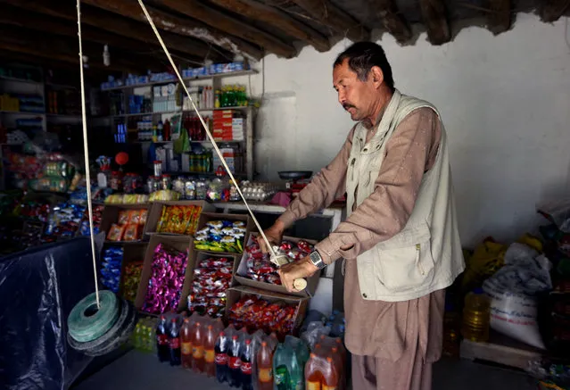 An Afghan shopkeeper exercises with a self made dumbbell at his shop in Kabul, Afghanistan, Tuesday, May 5, 2015. (Photo by Rahmat Gul/AP Photo)