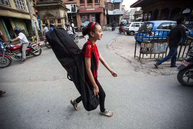 Samita Bajracharya walks carrying an Indian classic music instrument called Sarod on her way for her first ever public performance in Patan, Nepal, 12 May 2014. Samita enjoys playing Sarod classical music, which she has been learning by Nepal's famous musician Suresh Raj Bajracharya. (Photo by Narendra Shrestha/EPA)