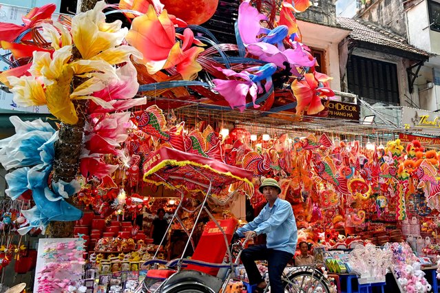 A cyclo driver passes by a shop selling decorative items in Hanoi on August 9, 2024, ahead of the Mid-Autumn Festival. (Photo by Nhac Nguyen/AFP Photo)