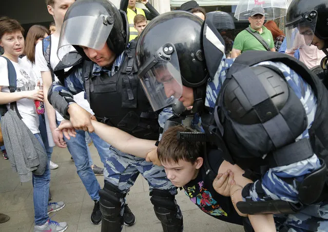 A young demonstrator is apprehended by riot police during a demonstration in downtown Moscow, Russia, Monday, June 12, 2017.  (Photo by Alexander Zemlianichenko/AP Photo)
