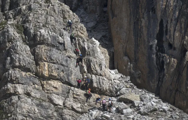 Climbers make their way up a via ferrata to the peak of Piz Da Lech in the Dolomite Mountains near the town of Corvara in northern Italy July 20, 2015. (Photo by Bob Strong/Reuters)