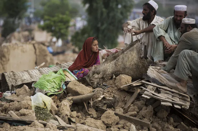 People sit on their belongings after their houses were bulldozed by the government, in slums of Islamabad, Pakistan, Friday, July 31, 2015. (Photo by B. K. Bangash/AP Photo)