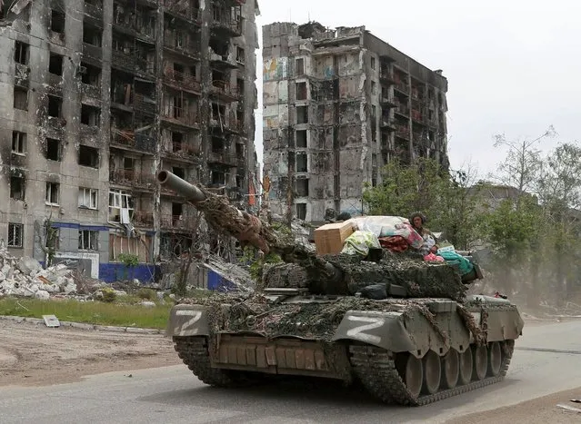 Service members of pro-Russian troops drive a tank along a street past a destroyed residential building during Ukraine-Russia conflict in the town of Popasna in the Luhansk Region, Ukraine on May 26, 2022. (Photo by Alexander Ermochenko/Reuters)