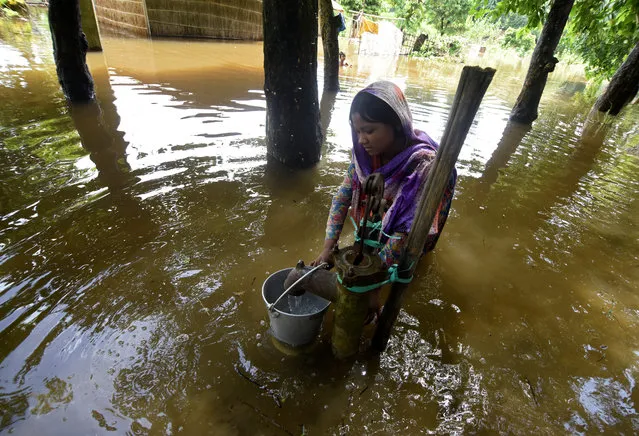 A girl fetches drinking water from a partially submerged hand pump in a flood-affected village in Morigaon district in Assam, July 5, 2017. (Photo by Anuwar Hazarika/Reuters)