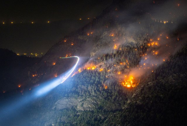 General view of a wildfire on the flank of a mountain in Bitsch near Brig, Switzerland on July 18, 2023. Picture taken with a long exposure. (Photo by Denis Balibouse/Reuters)