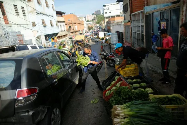 A man sells lettuce on a street near the municipal market in the popular neighborhood of Catia in Caracas, Venezuela on June 11, 2022. (Photo by Leonardo Fernandez Viloria/Reuters)