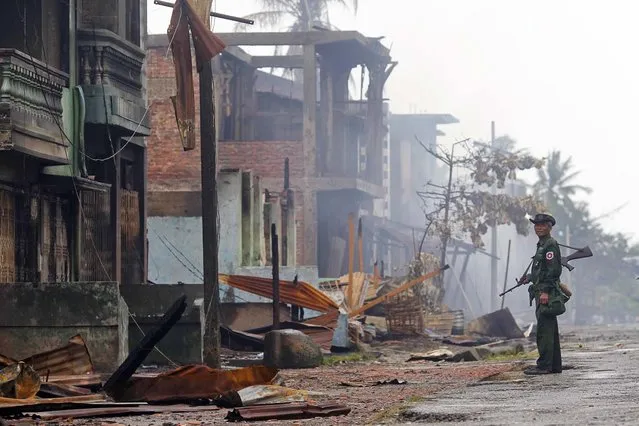 A soldier patrols through a neighbourhood that was burnt during recent violence in Sittwe June 14, 2012